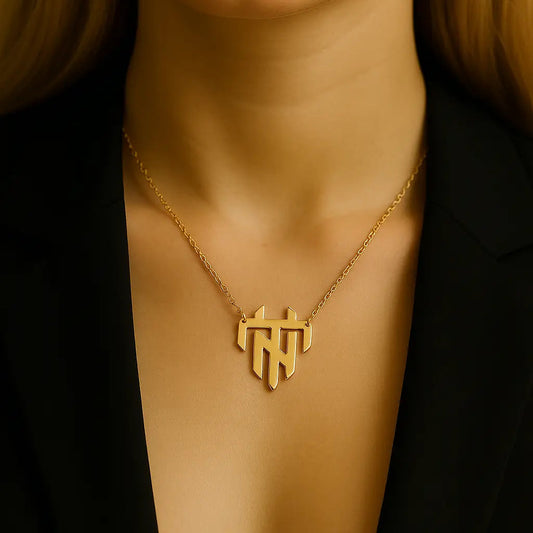 Gold necklace with a geometric pendant on a person wearing a black outfit.